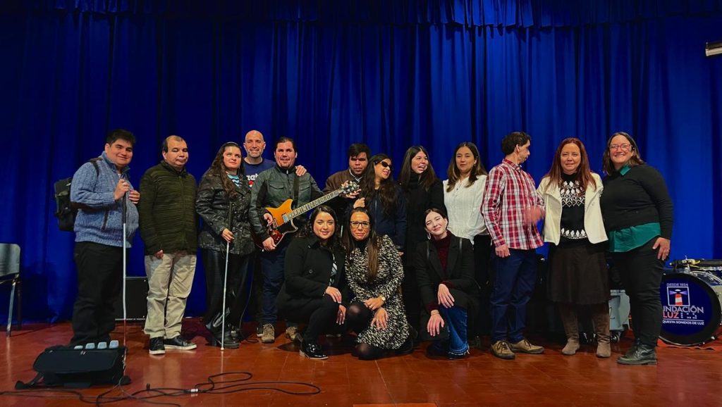 Integrantes de la Orquesta Sonidos de Luz posan sonrientes junto a trabajadores del Colegio Jorge Alessandri tras el exitoso concierto.